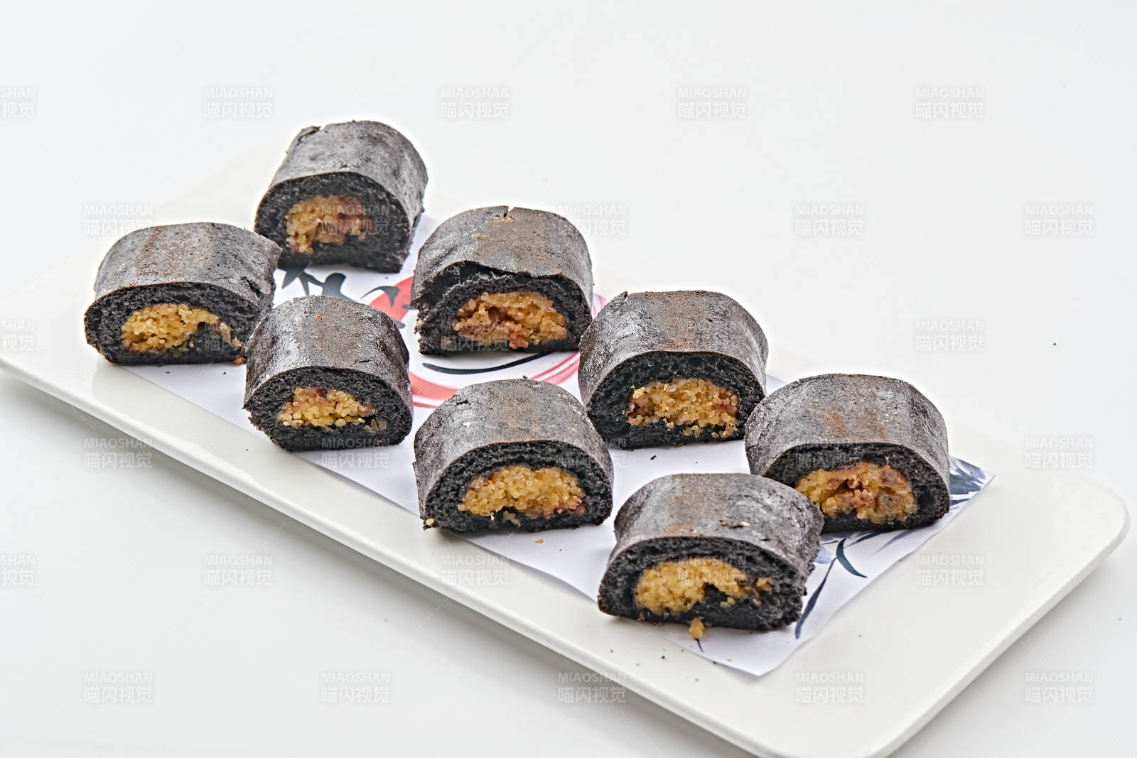 白色瓷盘装的紫米面小米杂粮卷图片