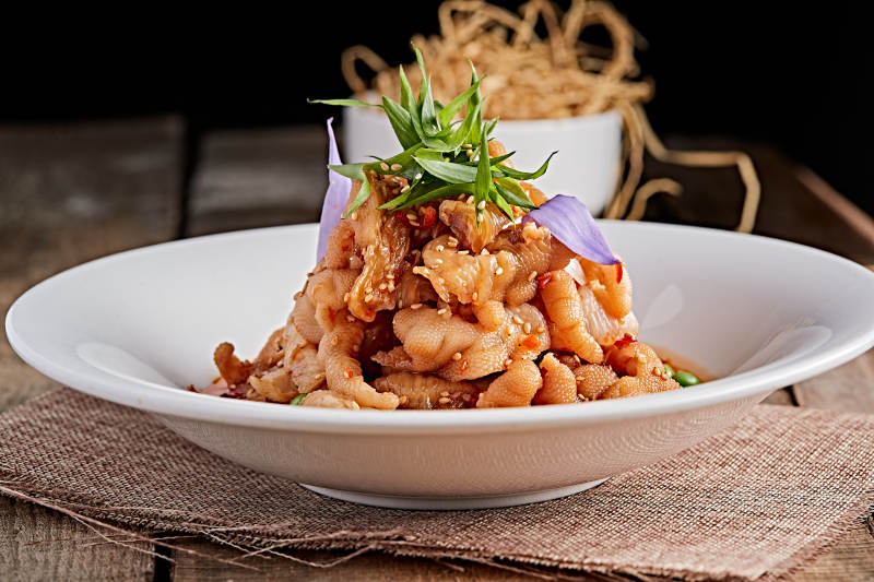 白色瓷盘装的红油酸辣脱骨凤爪图片