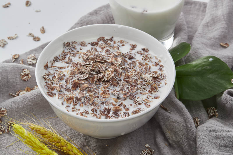 向装满低脂黑燕麦片的碗中倾倒牛奶图片