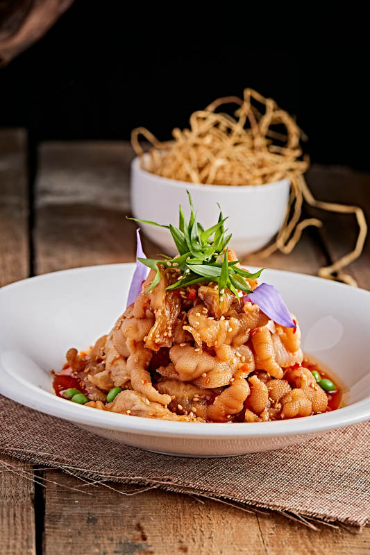 白色瓷盘装的红油酸辣脱骨凤爪图片