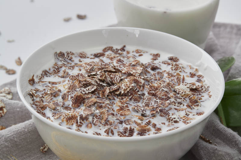 向装满低脂黑燕麦片的碗中倾倒牛奶图片