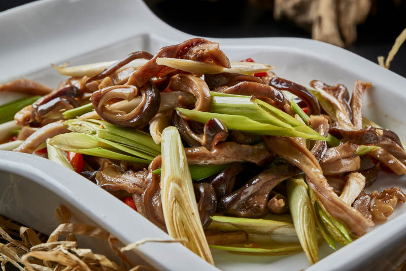 白瓷盘装的香辣青蒜炒猪肚丝图片