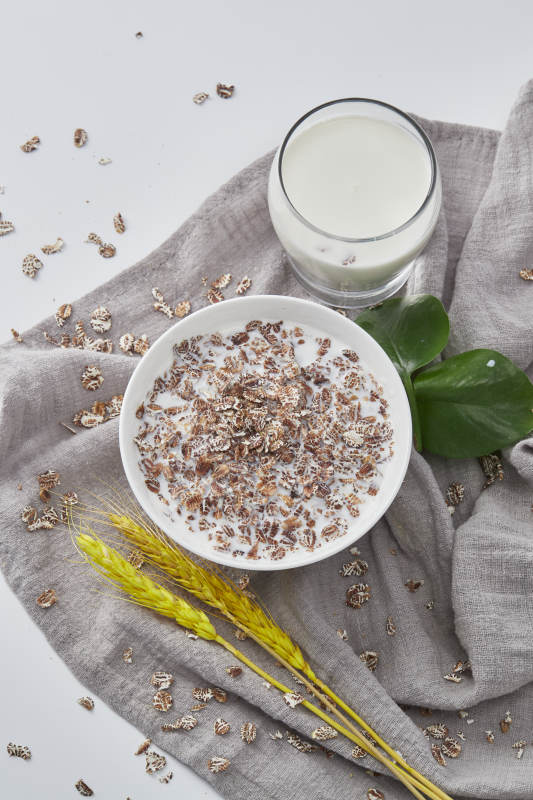 向装满低脂黑燕麦片的碗中倾倒牛奶图片