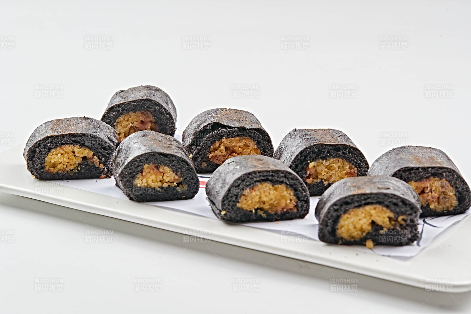 白色瓷盘装的紫米面小米杂粮卷图片