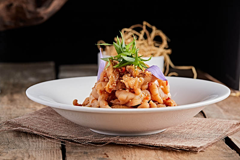 白色瓷盘装的红油酸辣脱骨凤爪图片