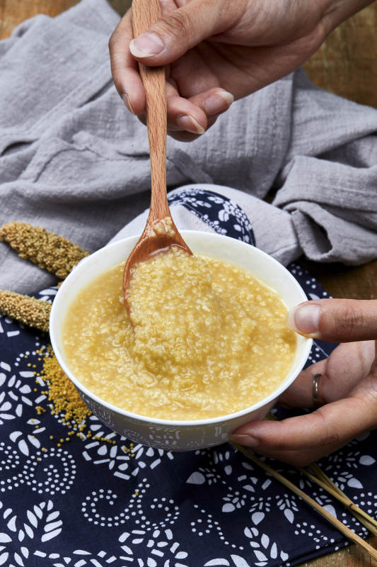 手持木勺㧟起的美味香浓小米粥图片