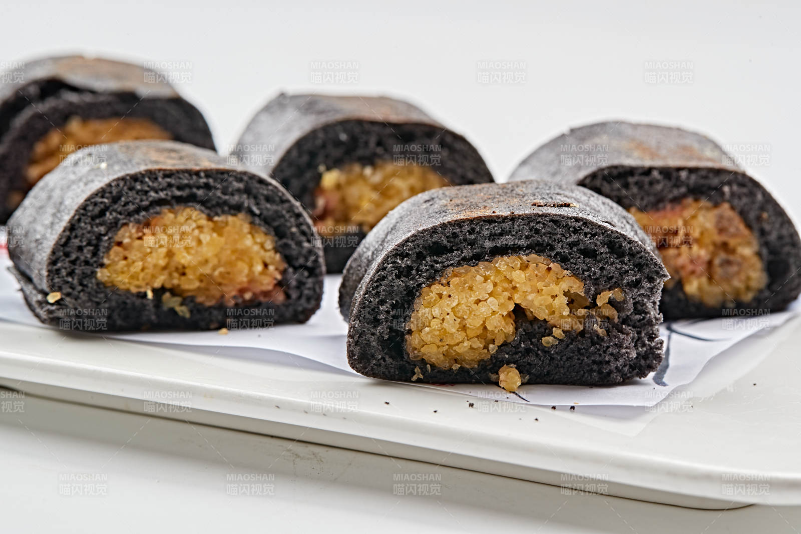 白色瓷盘装的紫米面小米杂粮卷图片