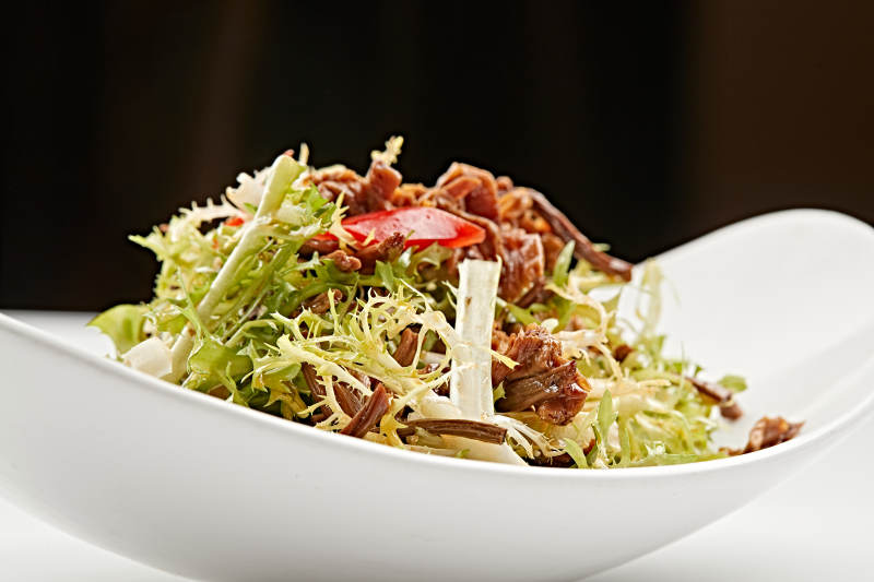 白色瓷盘装的苦菊炝拌茶树菇图片