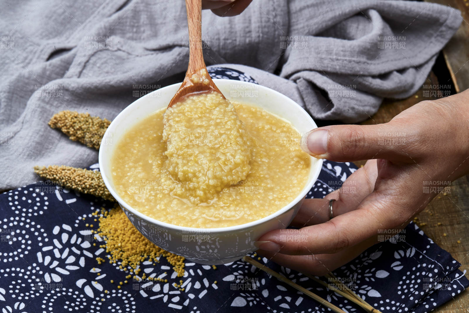 手持木勺㧟起的美味香浓小米粥图片