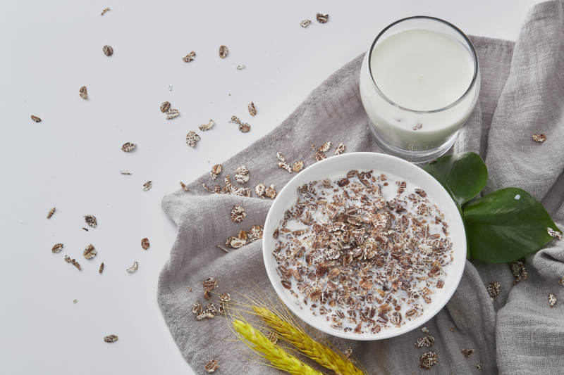 向装满低脂黑燕麦片的碗中倾倒牛奶图片