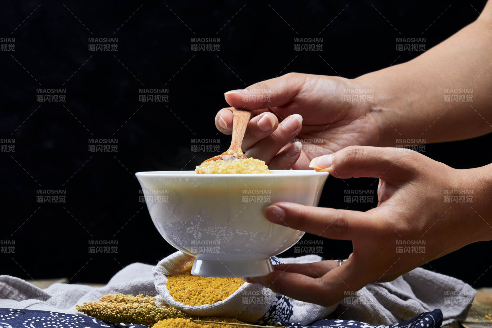 手持木勺㧟起的美味香浓小米粥图片