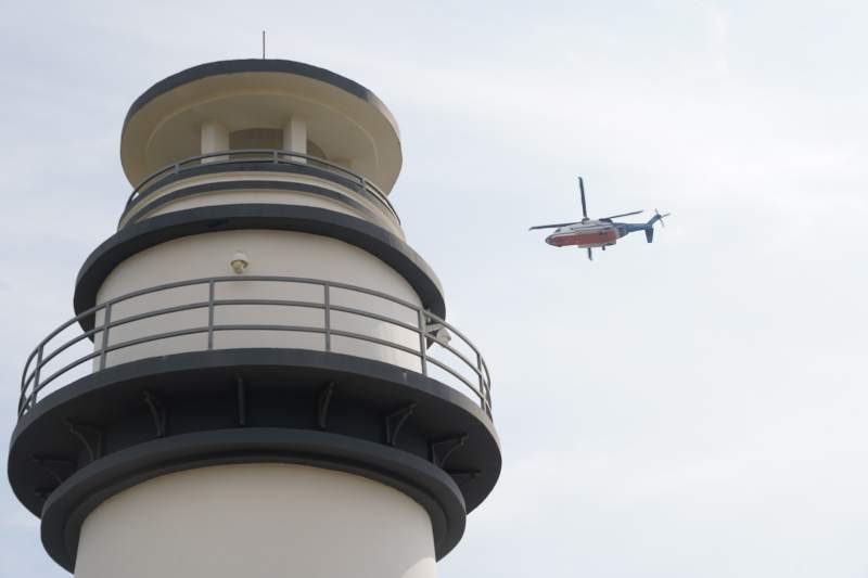 灯塔旁直升机飞过海岸图片