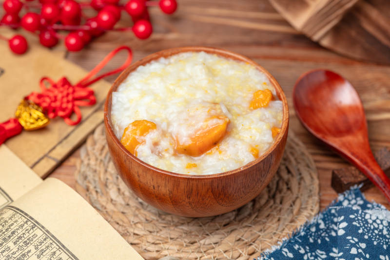 小米红薯粥配木碗图片