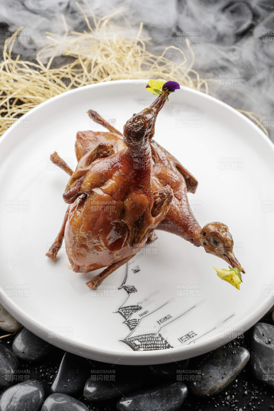 白色圆盘装的生炸乳鸽摆放在黑色鹅卵石上图片