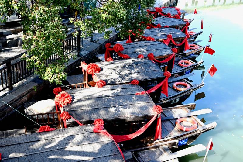 红绸装饰的古镇市河游船图片
