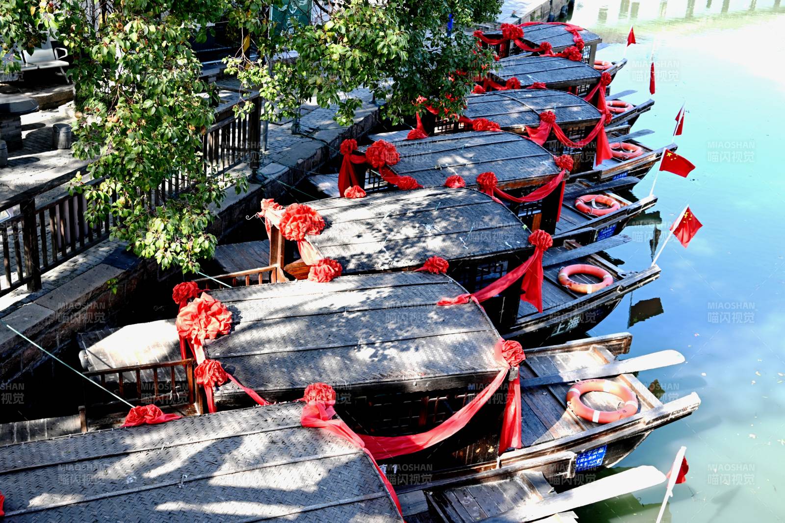 红绸装饰的古镇市河游船图片