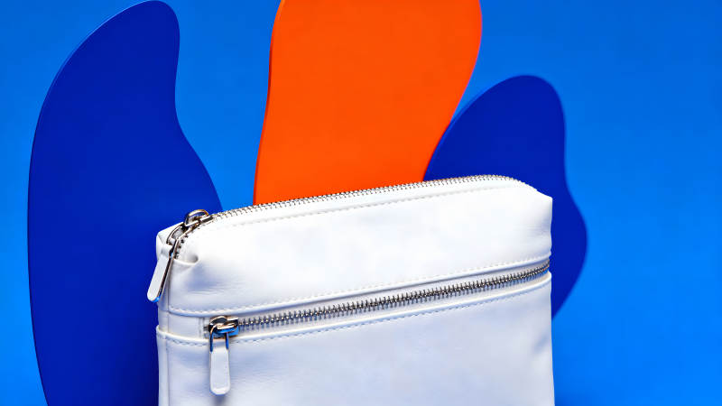 白色包包置于蓝色橙色背景上图片