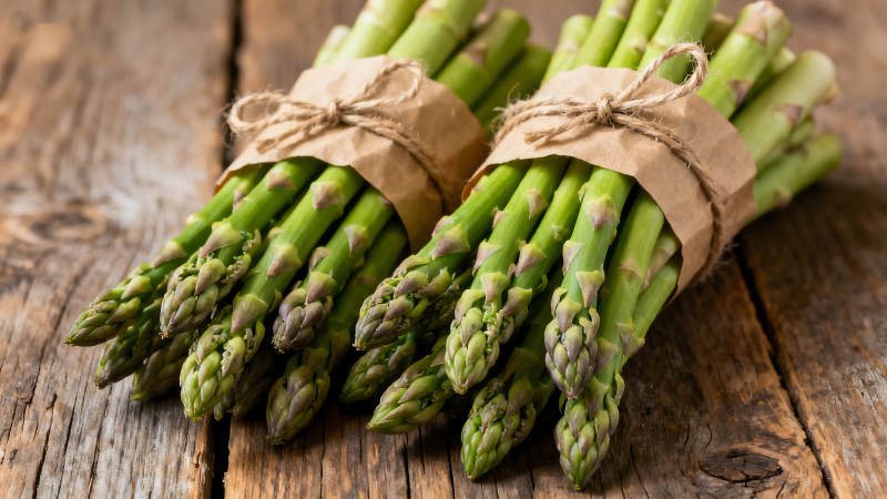 新鲜的芦笋捆绑在木质表面图片