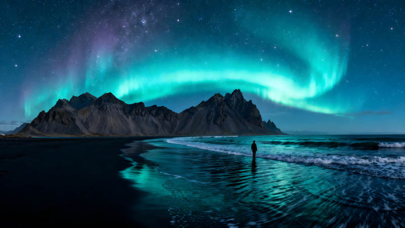 极光下的海滩与山脉下的剪影图片