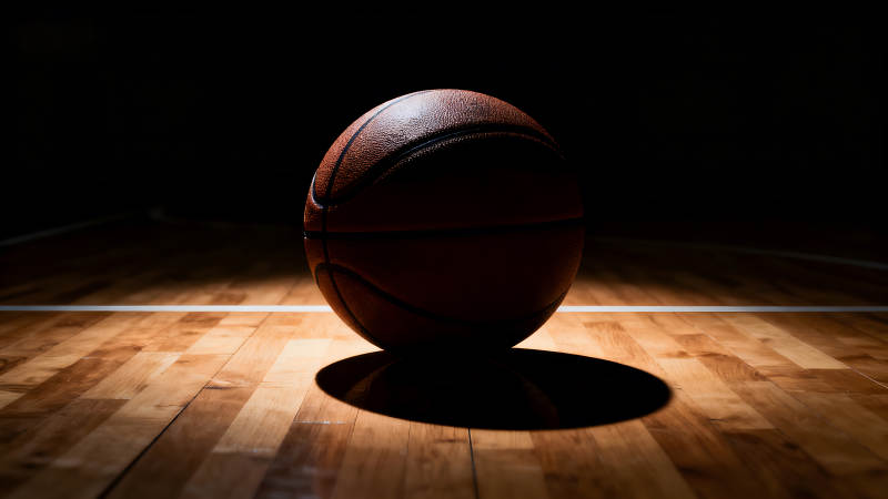 篮球在球场上光影下的特写图片