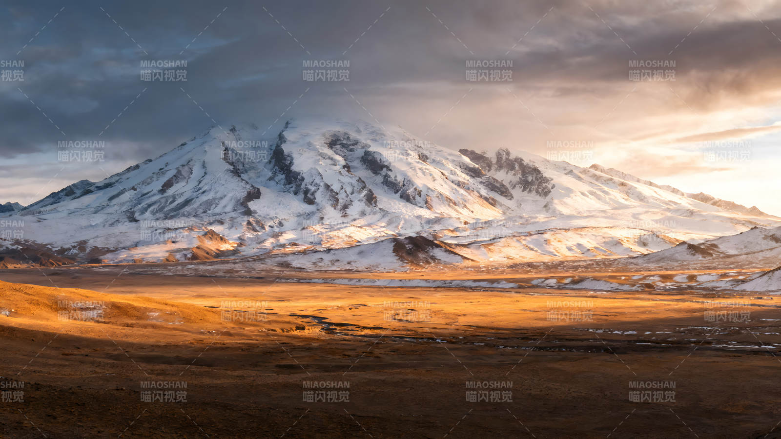 雪山下的金色平原阳光照射下的壮丽景色图片