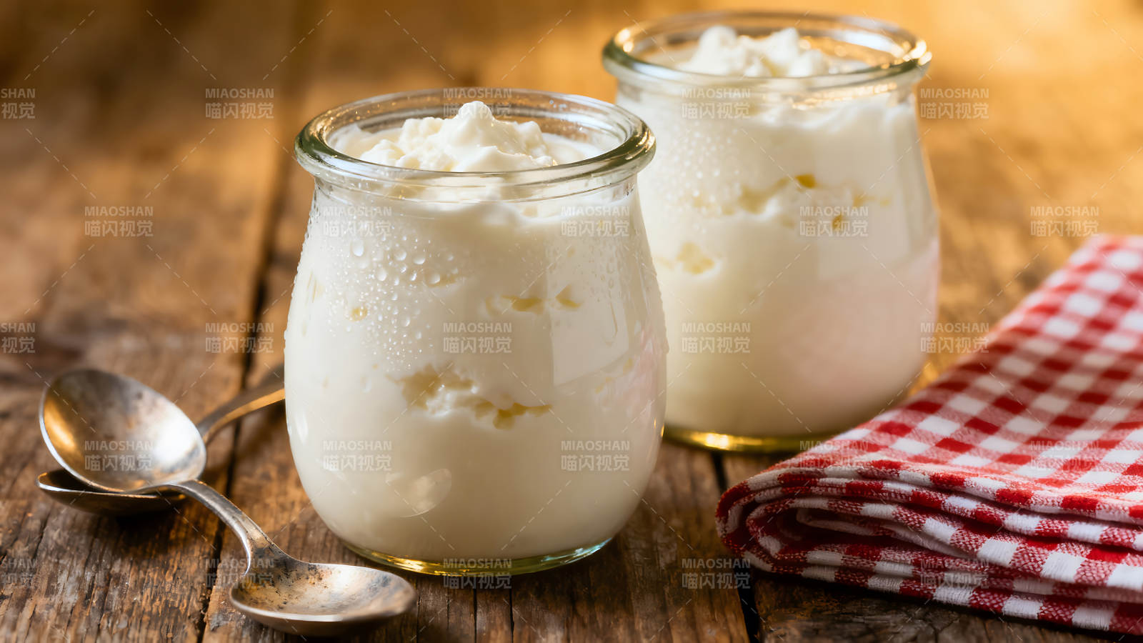 两杯酸奶放木桌上配勺子和餐巾图片