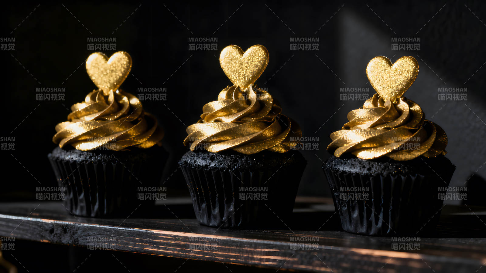 金色爱心纸杯蛋糕在黑色背景上图片
