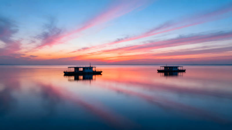 夕阳下水面平静的小船图片