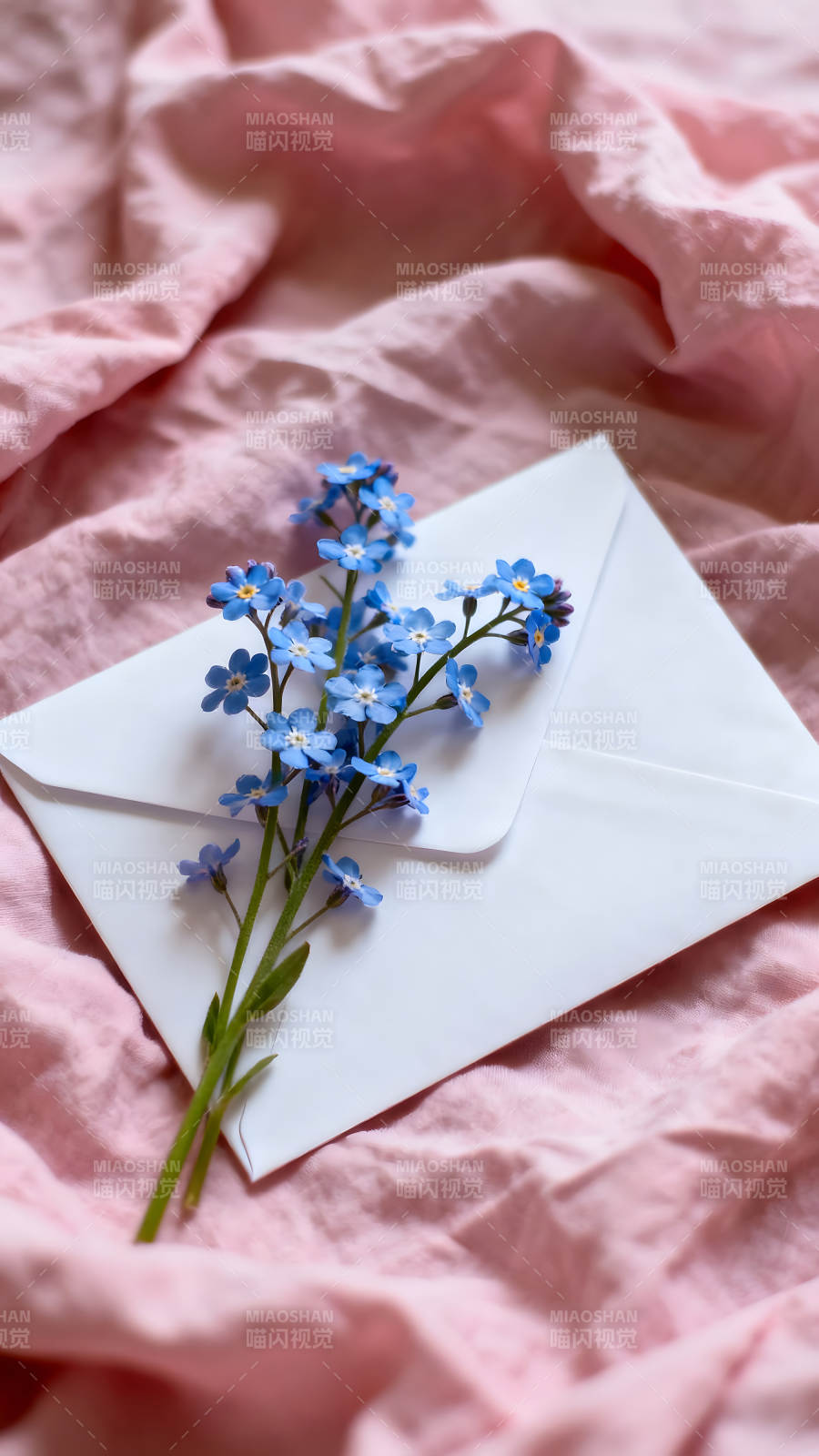 信封与勿忘我花束铺在粉色床单上图片