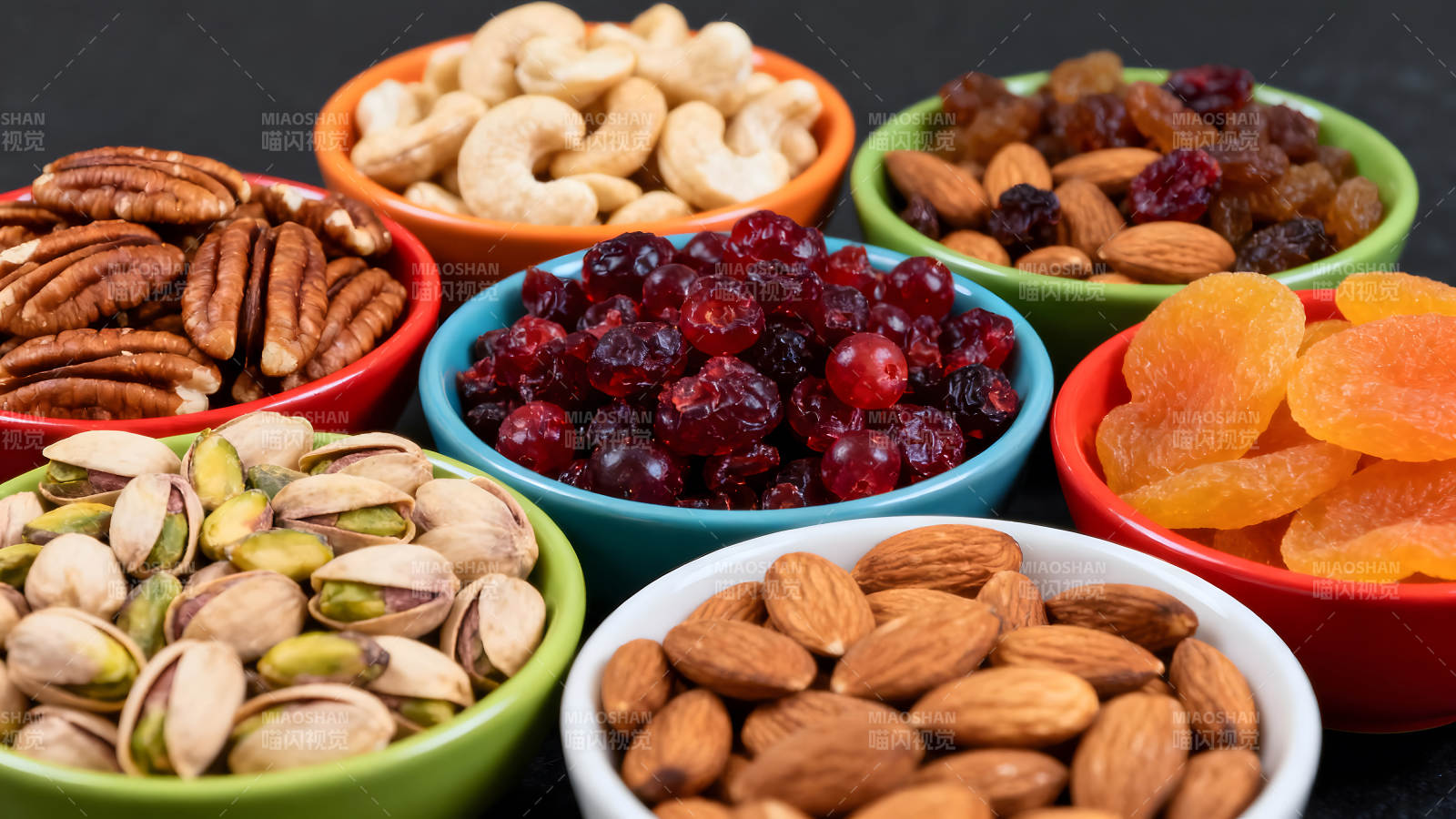 各种坚果和干果盛放在彩色的碗中图片