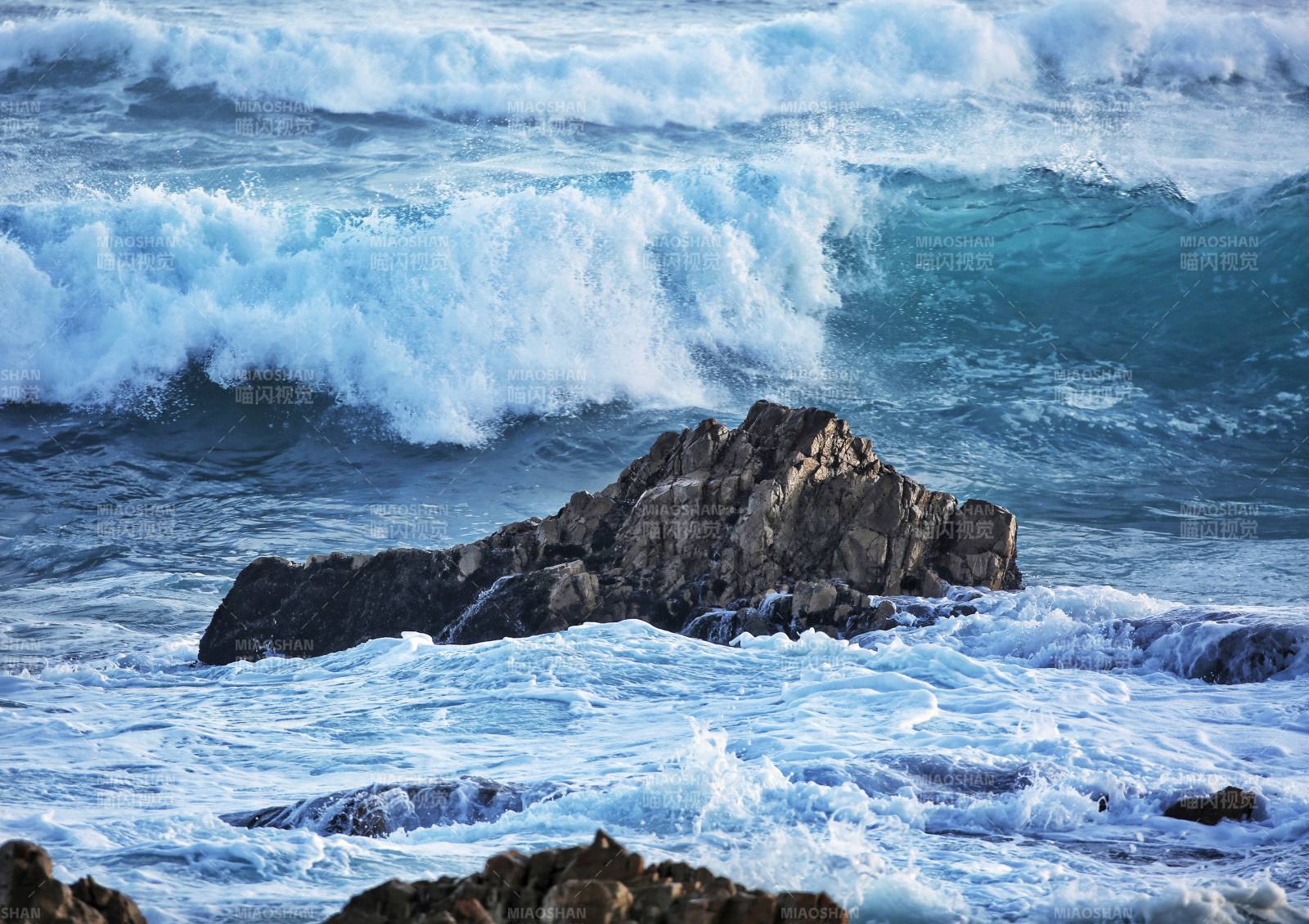 翻涌的蓝色海浪拍打海上礁石图片