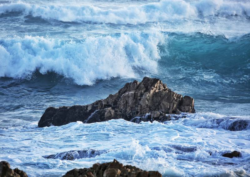 翻涌的蓝色海浪拍打海上礁石图片