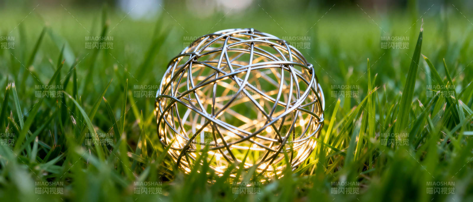 草地上发光的金属球图片
