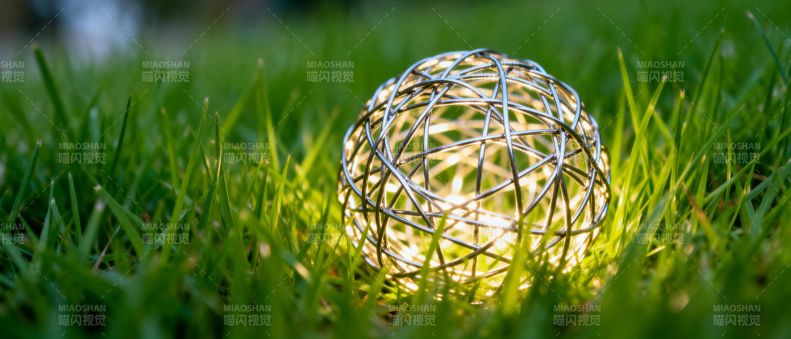 草地上发光的金属球图片