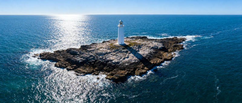 灯塔矗立海中岩岛图片