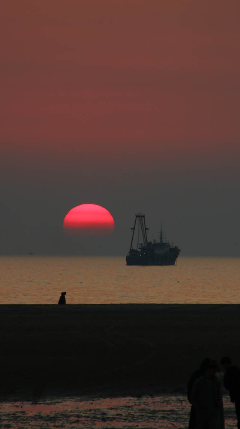 夕阳下的渔船剪影图片