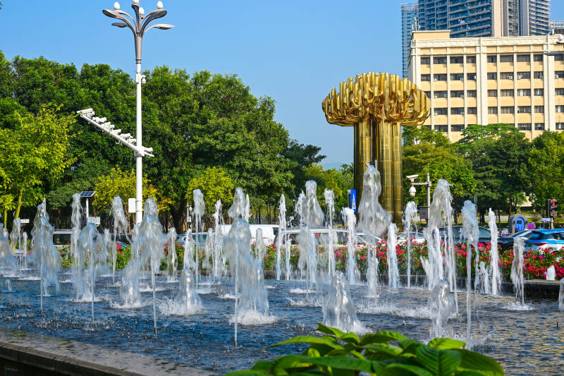 蓝天下城市广场金色雕塑与喷泉景观图片