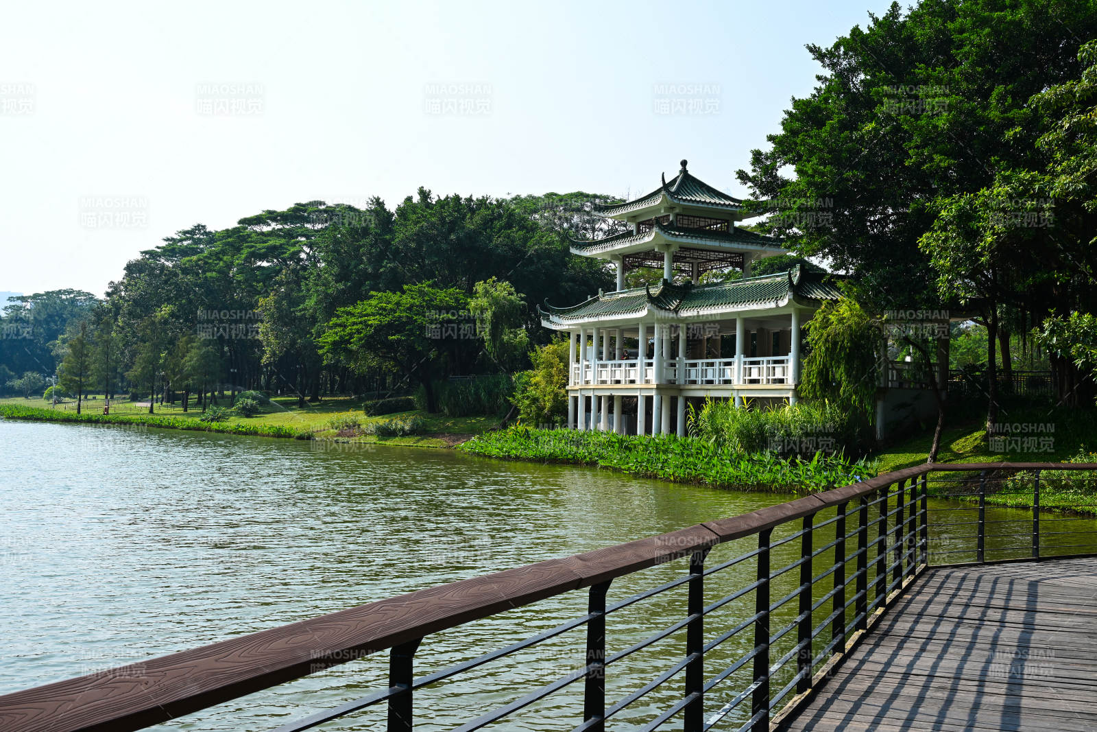 阳光下湖边中式楼阁与木质栈道景观图片