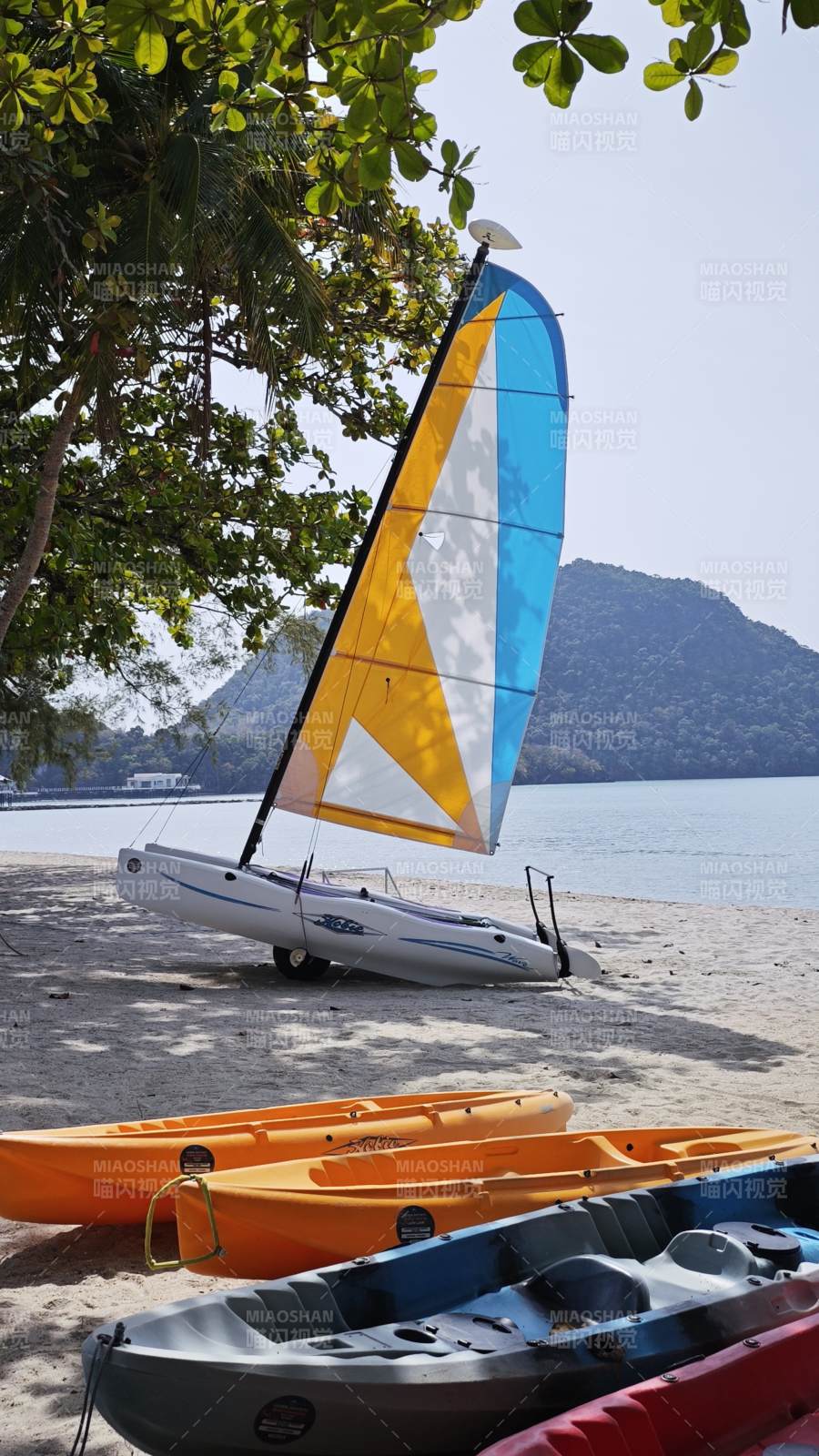 热带海岛沙滩上的帆船与皮划艇图片