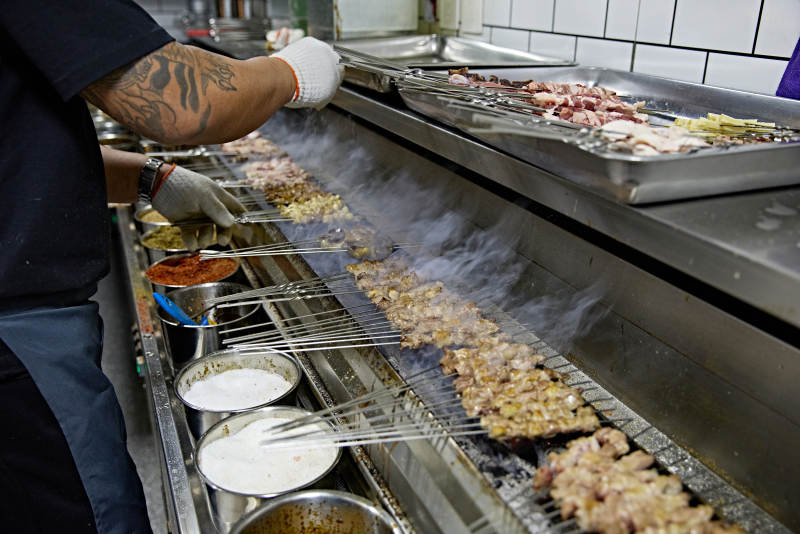 烧烤店后厨的厨师在烤炉上的烤制美食肉串图片