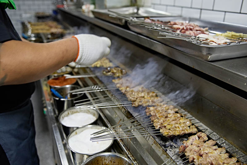 烧烤店后厨的厨师在烤炉上的烤制美食肉串图片