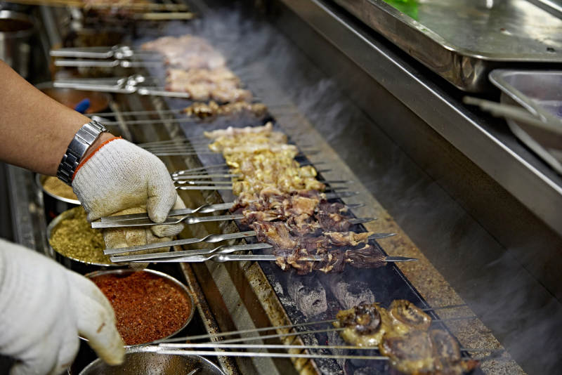 烧烤店后厨的厨师在烤炉上的烤制美食肉串图片