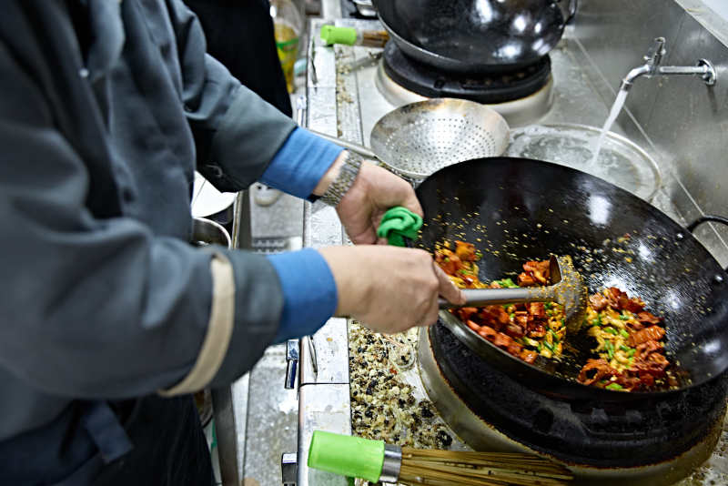 人与食物紧张忙碌的中餐厨房炒制辣子鸡丁图片