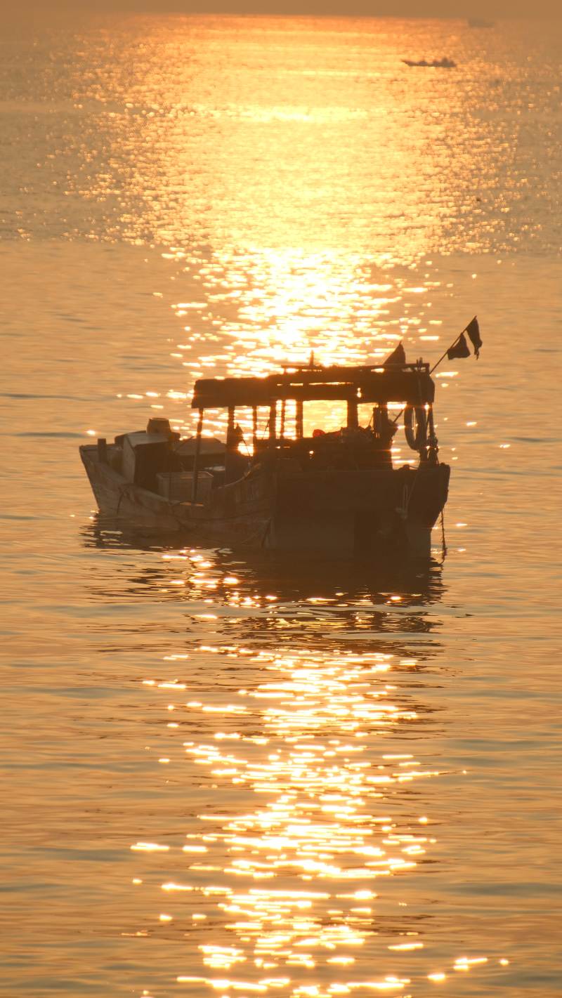 夕阳下的渔船剪影图片