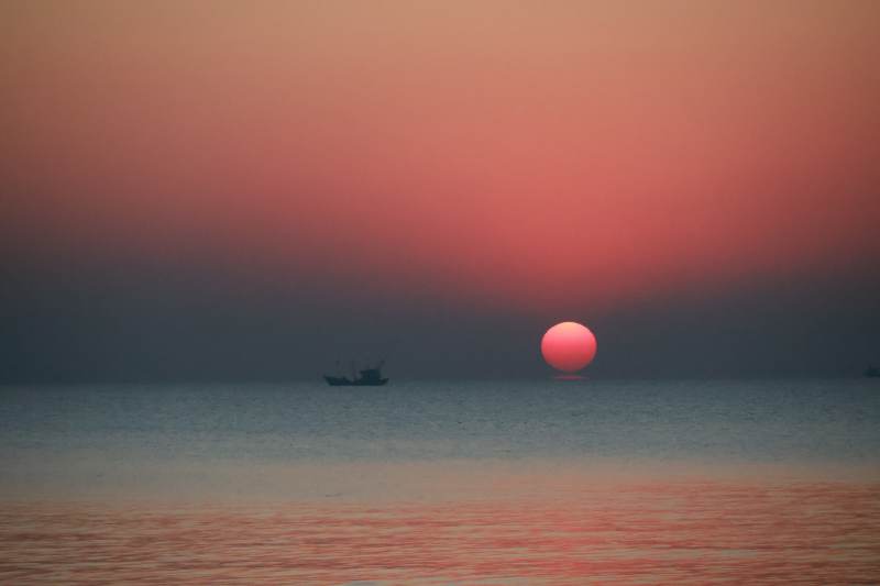 日出海面渔船影图片
