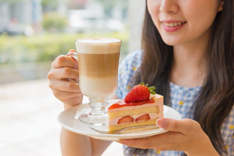 女子手持咖啡与草莓蛋糕图片