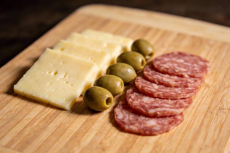 木质砧板上的奶酪香肠橄榄图片