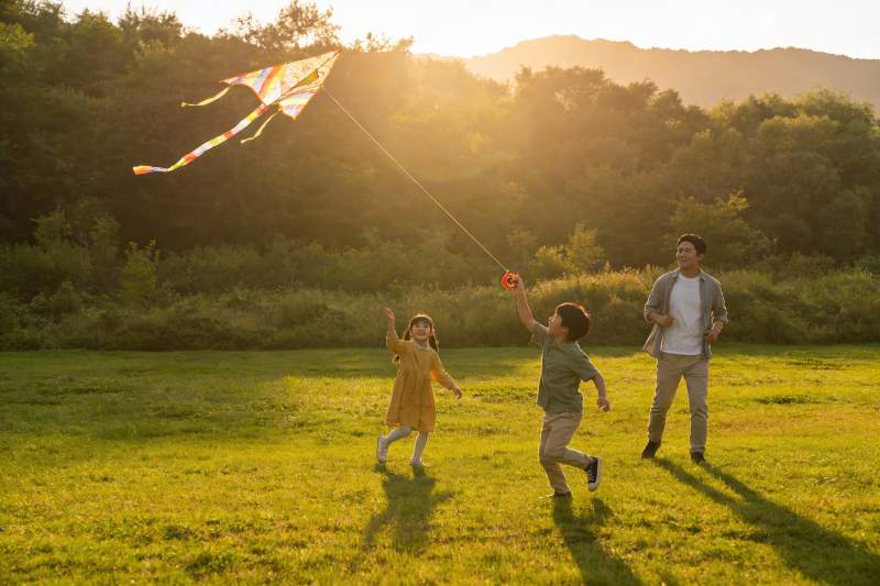 夕阳下父子三人放风筝图片