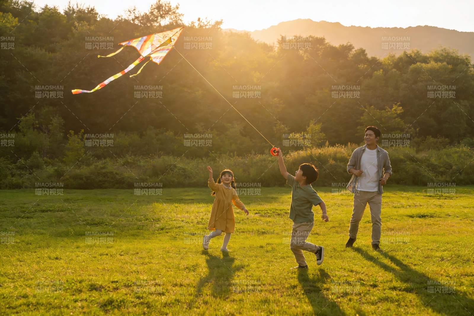 夕阳下父子三人放风筝图片