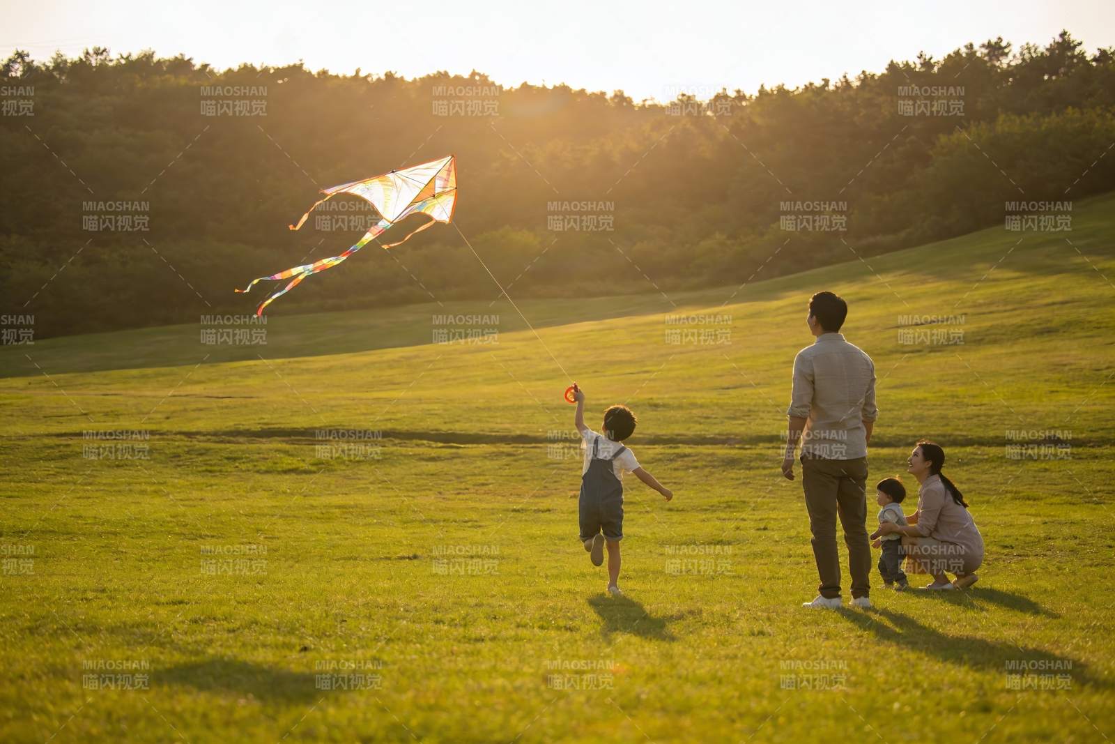 夕阳下草地放风筝的温馨家庭图片